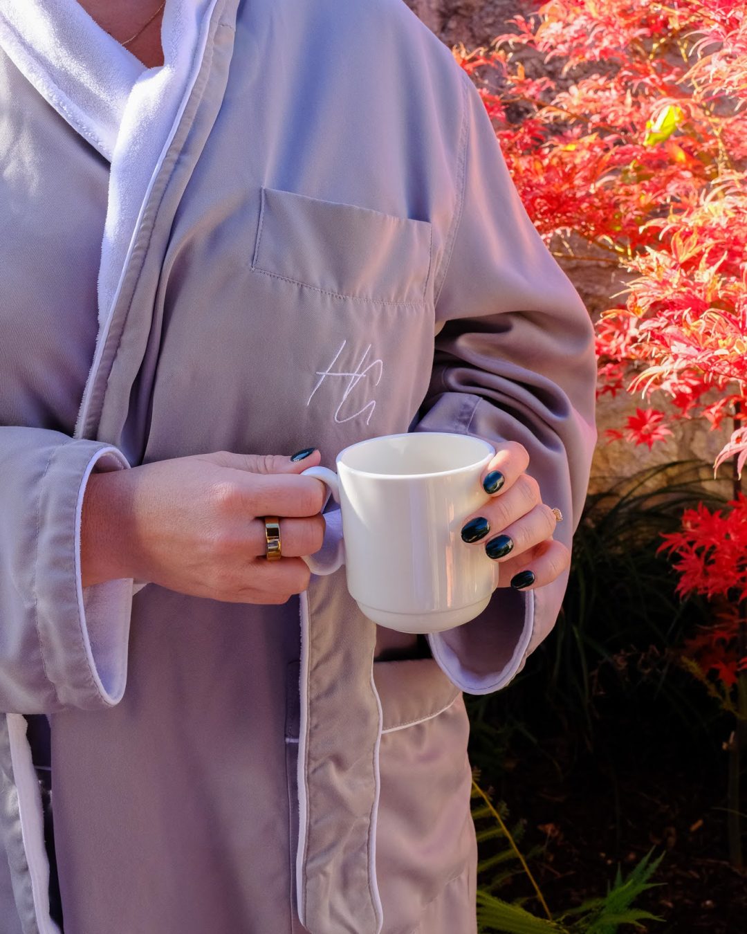 A woman poses in an Herb Garden robe with a cup of hot tea on the patio.